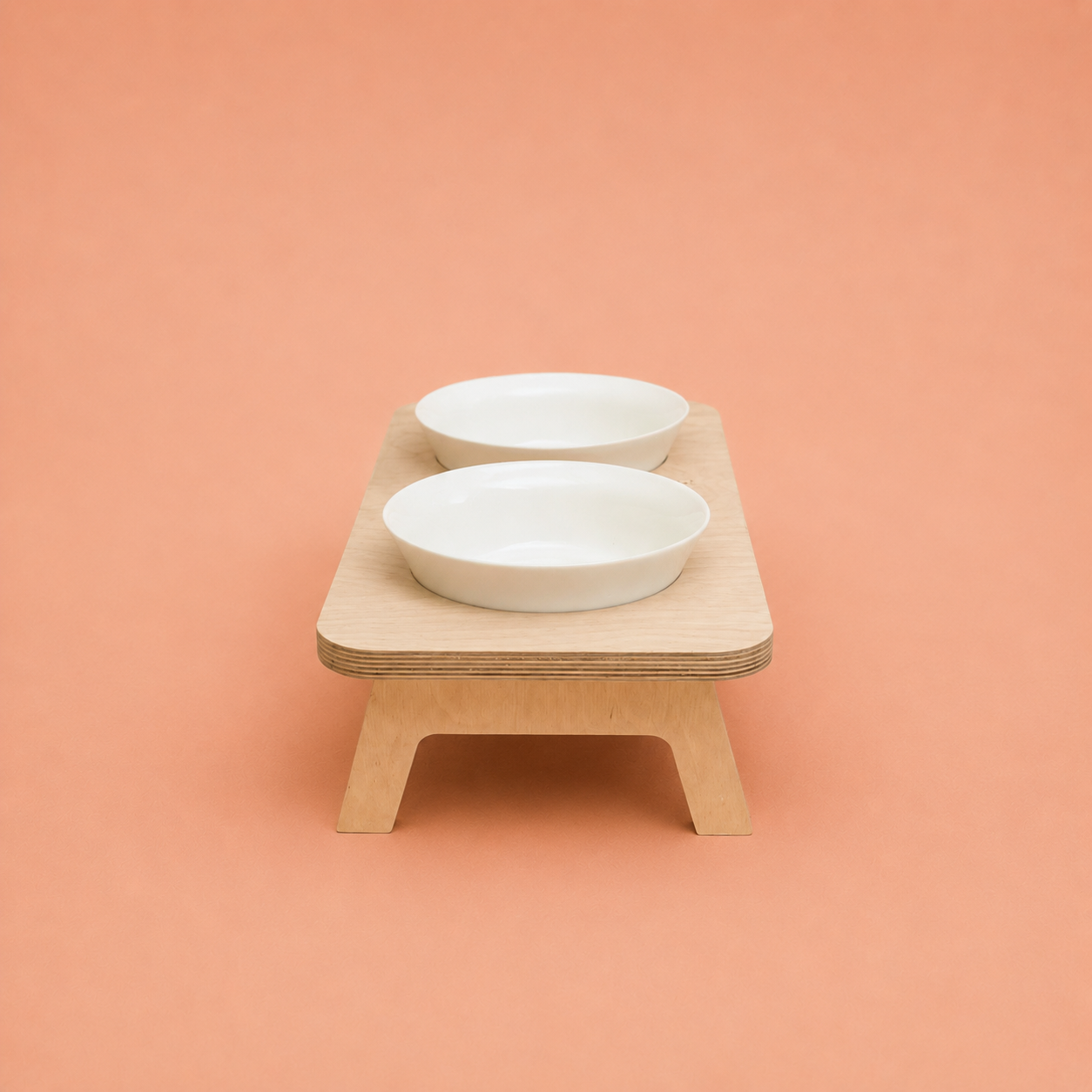 The FORM elevated feeder from the front, a deep wooden frame holding both bowls at a kinder height, made in Egypt by PawLuxe.